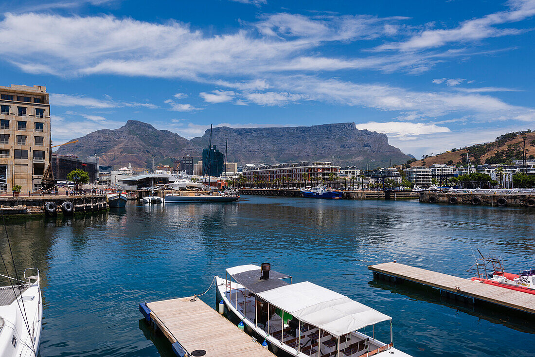 Boats moored along the harbor at the Victoria and Alfred Waterfront in Cape Town with Devil's Peak and Table Mountain in the background; Cape Town, Western Cape, South Africa