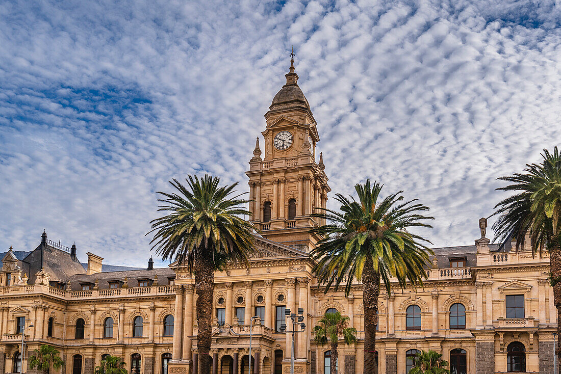 Palm trees in front of the facade of the Cape Town City Hall against a cloudy blue sky; Cape Town, Western Cape, South Africa