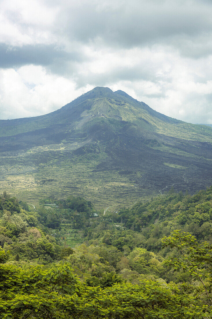 Überblick über den Mount Batur (Vulkan Kintamani) in South Batur mit bewölktem Himmel und üppiger Vegetation; Kintamani, Bangli Regency, Bali, Indonesien