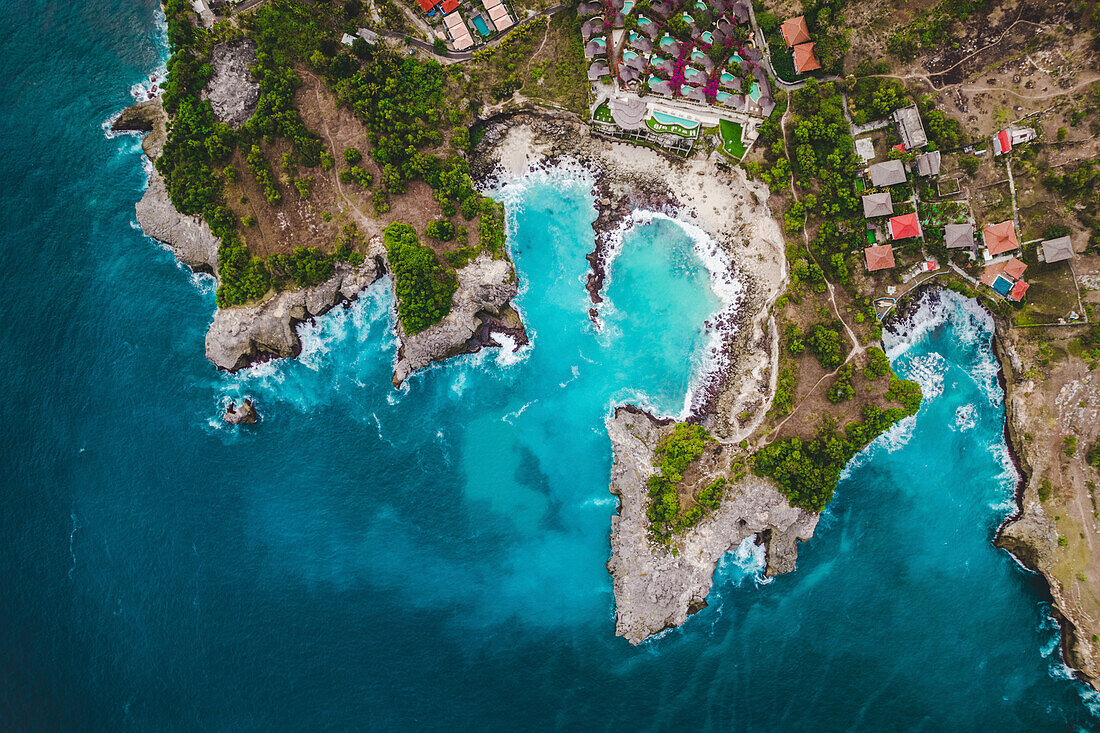 Blick von oben auf die felsige Küste und den Strand des Ferienortes Lembongan mit Gebäuden am Rande des türkisfarbenen Wassers vor der Küste Balis; Nusa Islands, Klungkung Regency, Ost-Bali, Indonesien