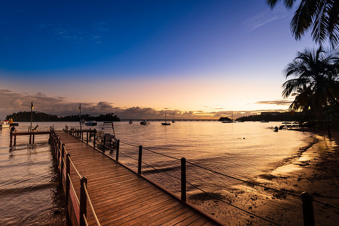 View of Samana Bay from a dock at sunset with boats moored in the harbor along the shores of Samana; Samana Peninsula, Dominican Republic, Caribbean