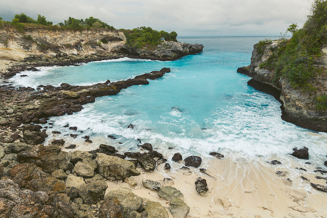 The rocky coast and beachfront of the resort town of Lembongan at the edge of the turquoise waters off the coast of Bali; Nusa Islands, Klungkung Regency, Indonesia