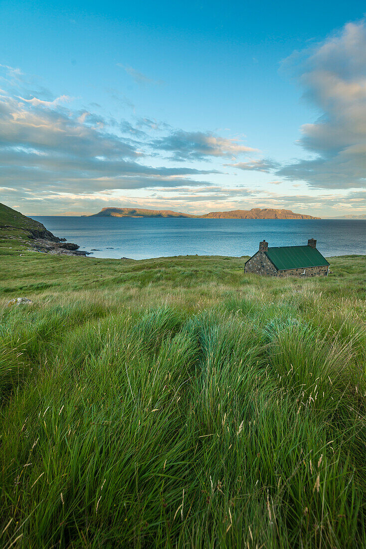 Dibidil Bothy at dusk with the Isle of Eigg in the background, Rum; Scotland, United Kingdom