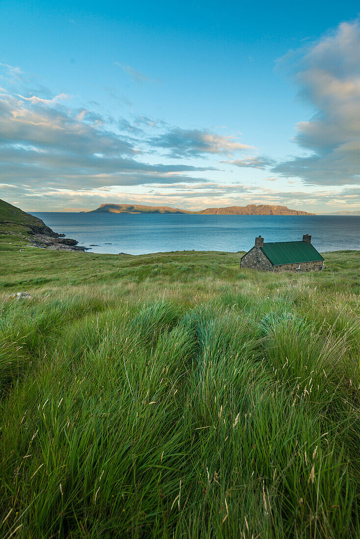Dibidil Bothy in der Abenddämmerung mit der Isle of Eigg im Hintergrund, Rum; Schottland, Vereinigtes Königreich