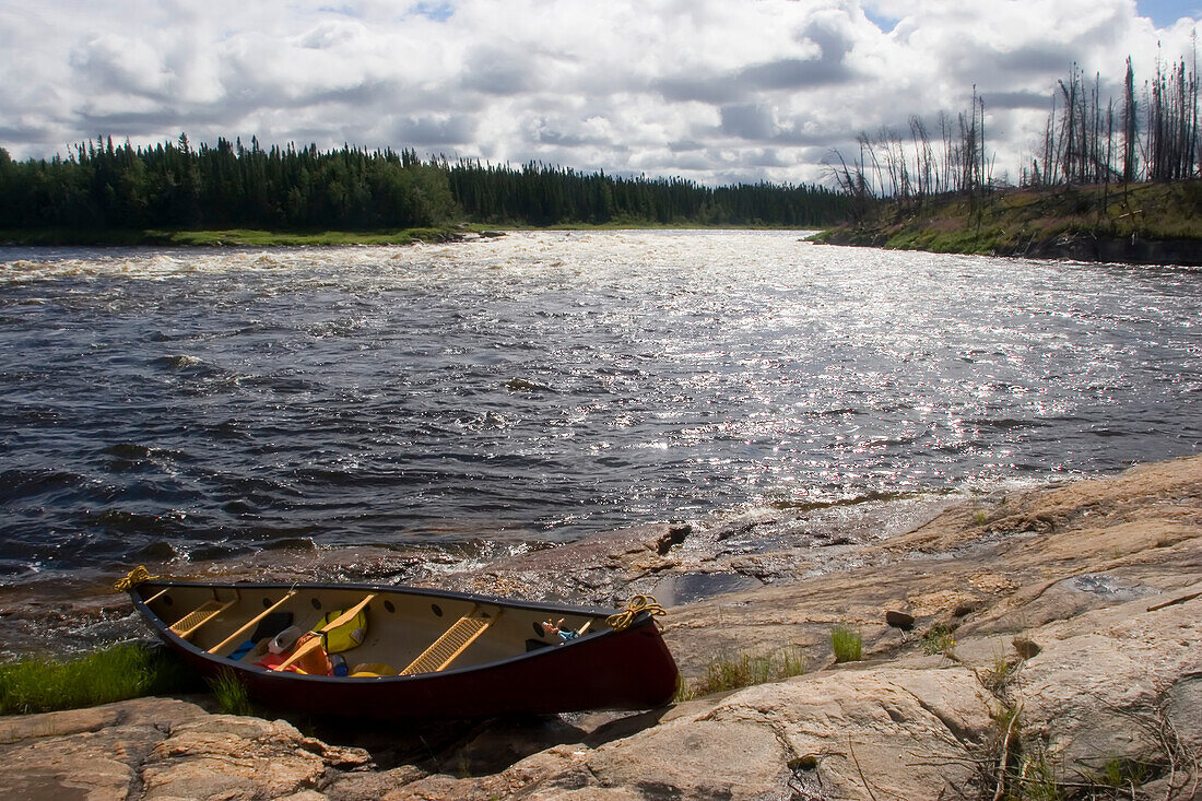 Ein Kanu, das an ein felsiges Ufer gezogen wurde; Winisk River, Ontario, Kanada.