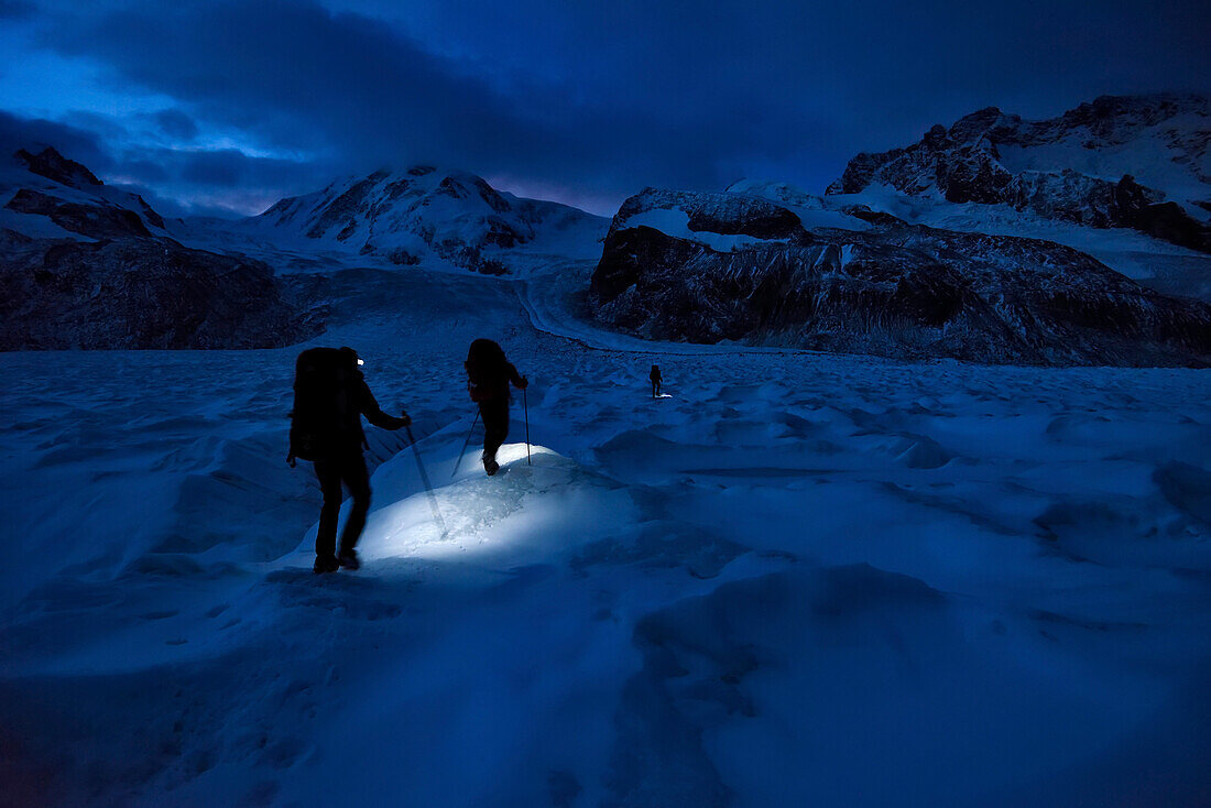 Höhlenforscher wandern über den Gletscher auf der Suche nach neuen, unerforschten Gletschermulden am Gornergletscher; Gornergrat, Zermatt, Schweiz.