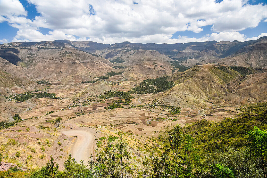 Schotterstraße durch das äthiopische Hochland mit einem ländlichen Bergbauerndorf im Norden Äthiopiens; Äthiopien