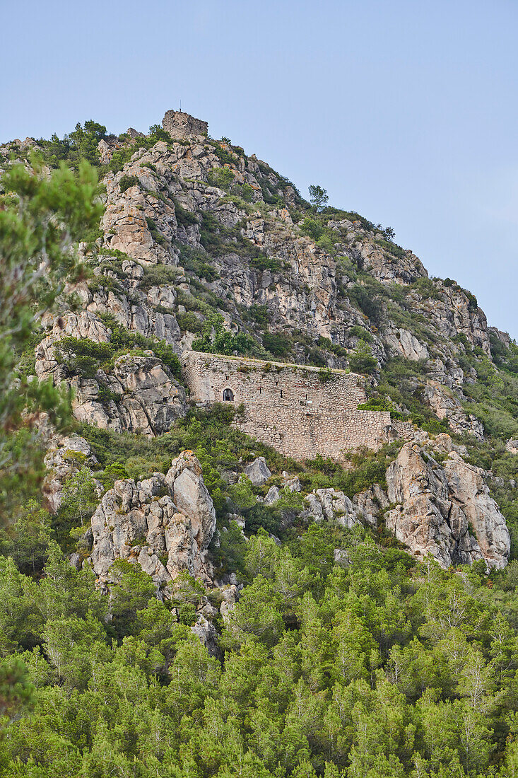 Old, stone built structure in the cliffs on a mountainside in morning light, Parc Natural dels Ports; Catalonia, Spain