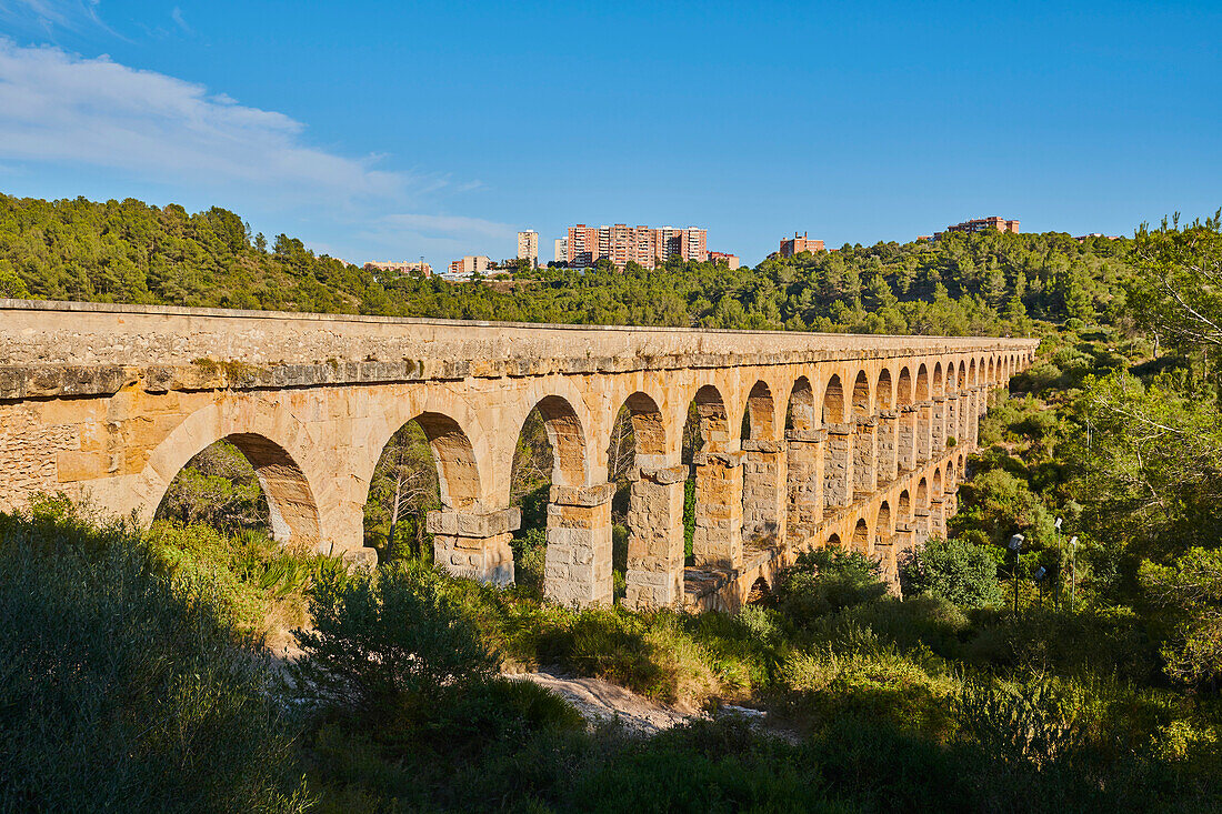 Altes, römisches Aquädukt, das Ferreres-Aquädukt (Aq?e de les Ferreres), auch bekannt als Pont del Diable (Teufelsbrücke), im Kontrast zu den modernen Gebäuden von Tarragona in der Ferne; Katalonien, Spanien