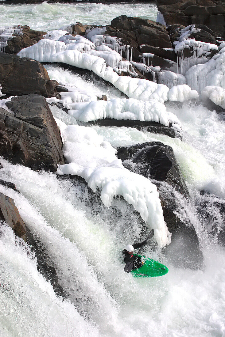 Wildwasserkajakfahrer fährt im Winter über einen fast gefrorenen Wasserfall; Great Falls, Potomac River, Maryland.