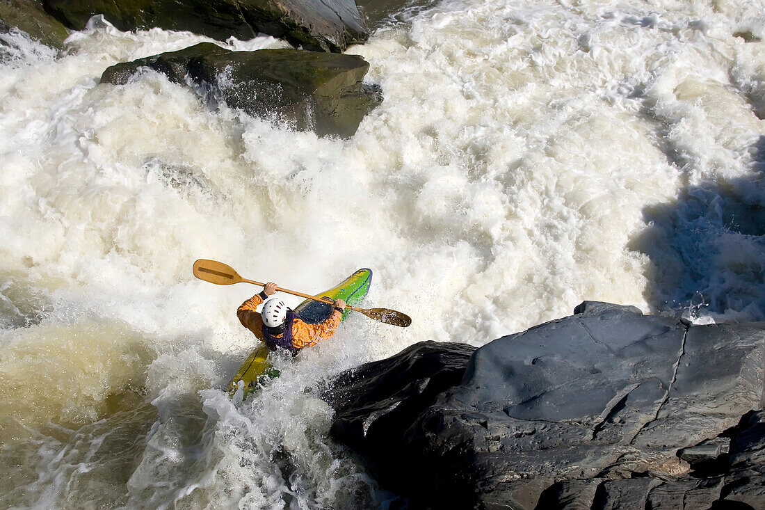 Ein Kajakfahrer paddelt von einem Wasserfall in großes Wildwasser; Great Falls, Potomac River, Virginia.