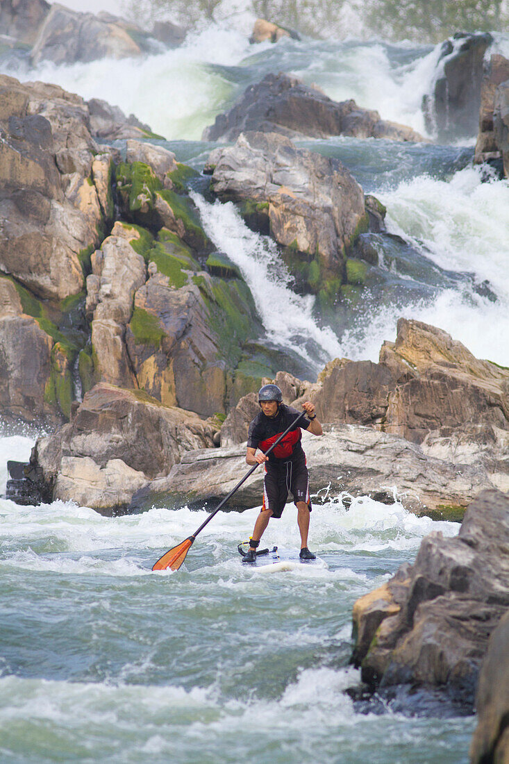 A stand up paddle boarder in white water just below Great Falls.; Potomac River, Maryland/Virginia.