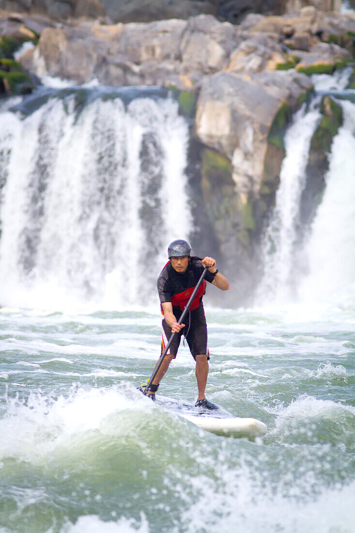 A stand up paddle boarder in white water just below Great Falls.; Great Falls, Potomac River, Maryland/Virginia.
