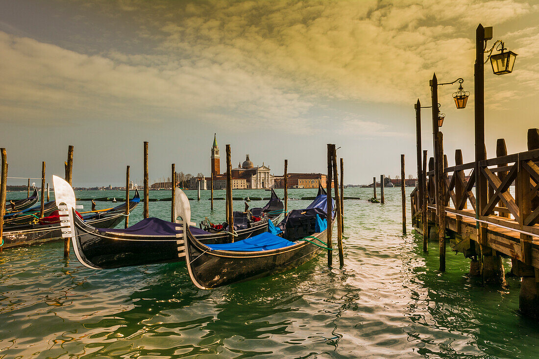 Blau verkleidete Gondeln am Ufer und Blick auf den Markusplatz über die Lagune in Venedig; Venedig, Venetien, Italien