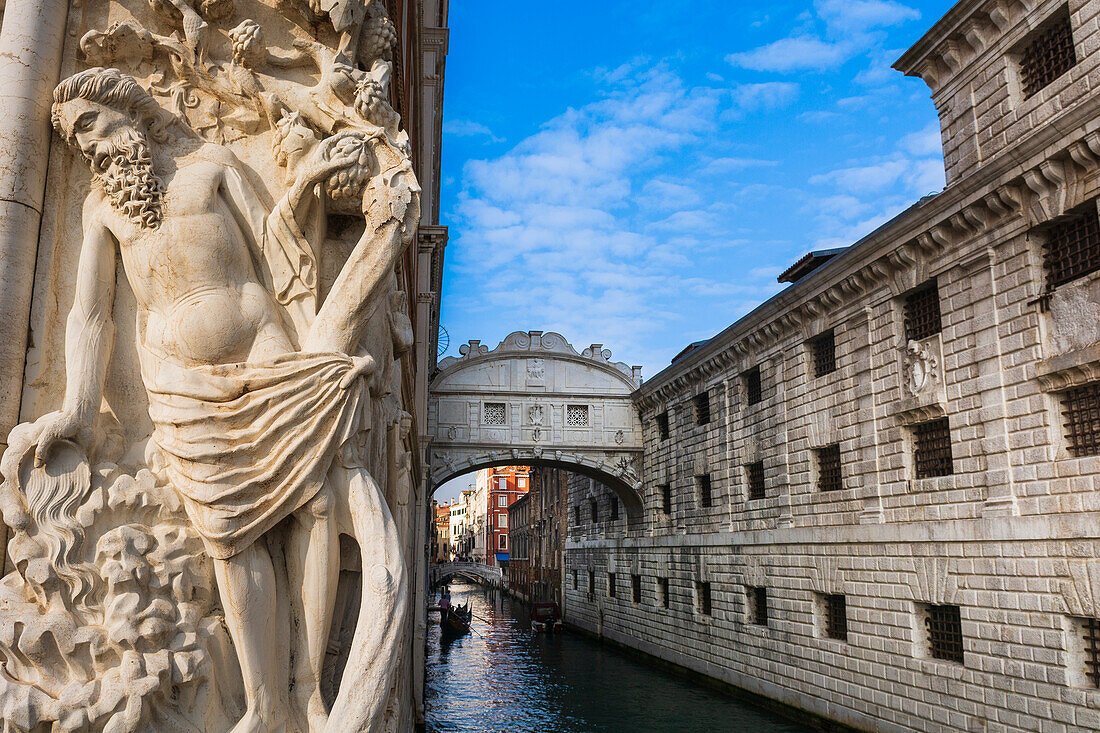 Legendary, Bridge of Sighs over the Rio di Palazzo, between Doge's Palace and the prisons with gondola passing underneath and relief sculpture on the exterior, palace wall in Veneto; Venice Italy