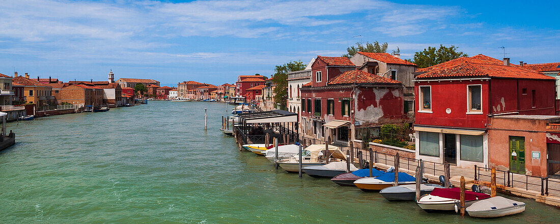 Typische Gebäude und Boote säumen das Ufer entlang des Kanals auf der Insel Murano in Venetien; Murano, Venedig, Italien