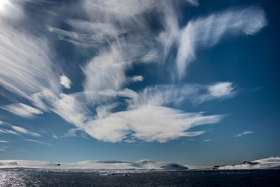 Dramatic cirrus clouds in a blue sky over the ice and snow on the wind-lashed Anderson Island in Antarctic Sound; Antarctica