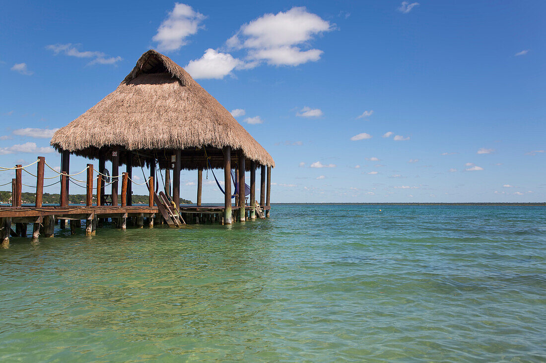 Tiki-Hütten-Pavillon auf dem Steg mit türkisfarbenem Wasser im Rancho Encantado Eco-Resort & Spa in Bacalar; Quintana Roo, Mexiko