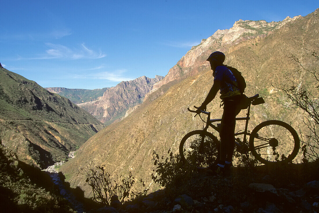 Ein Motorradfahrer macht eine Pause am Rande einer Schlucht; Batopillas Canyon, Sierra Madre Mountains, Mexiko.