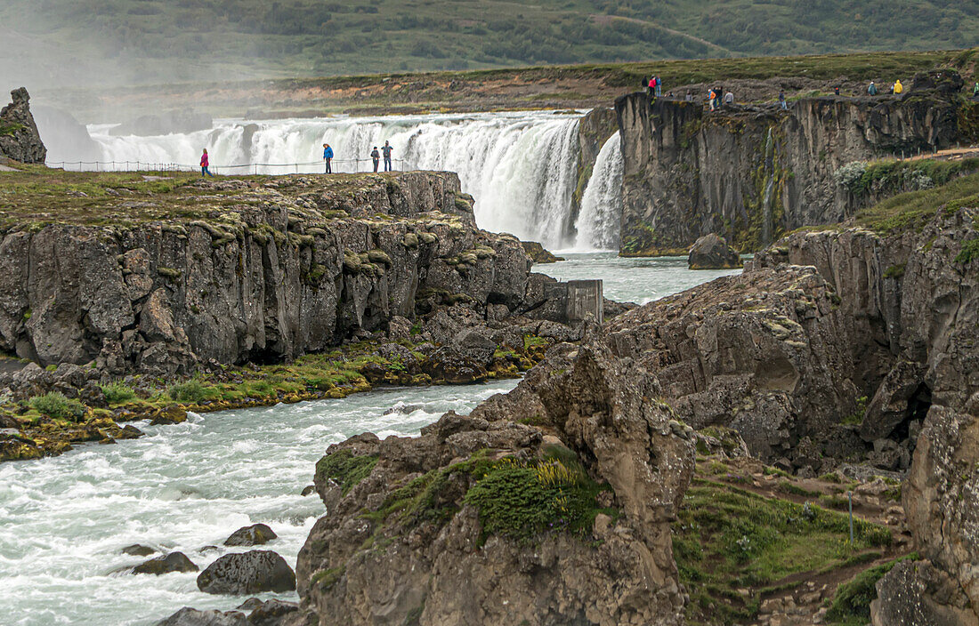 Menschen betrachten das sprudelnde Wasser des Go?ss-Wasserfalls. Godafoss liegt in Nordisland, etwa 45 Minuten von Akureyri, der zweitgrößten Stadt Islands, entfernt. Das Wasser, das aus dem Fluss Skj?andaflj?? stammt, stürzt aus einer Höhe von 36 Fuß; Nord-Zentral-Region, Island