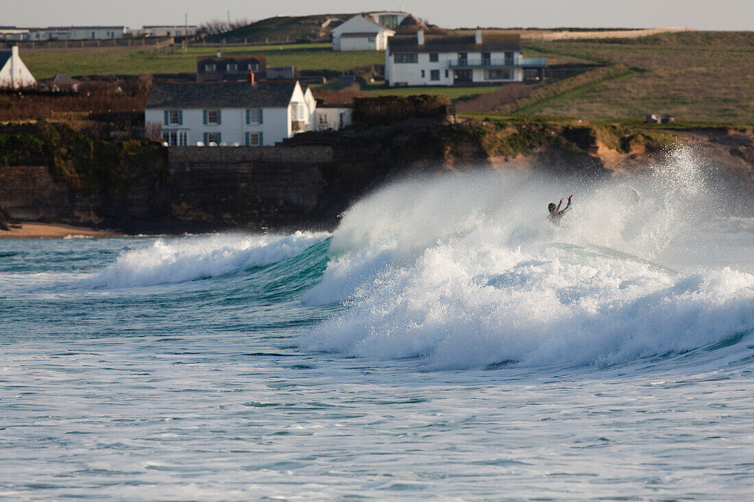 Person enjoying the cresting ocean waves in Constantine Bay near Padstow; Constantine Bay, Cornwall, England, Great Britain