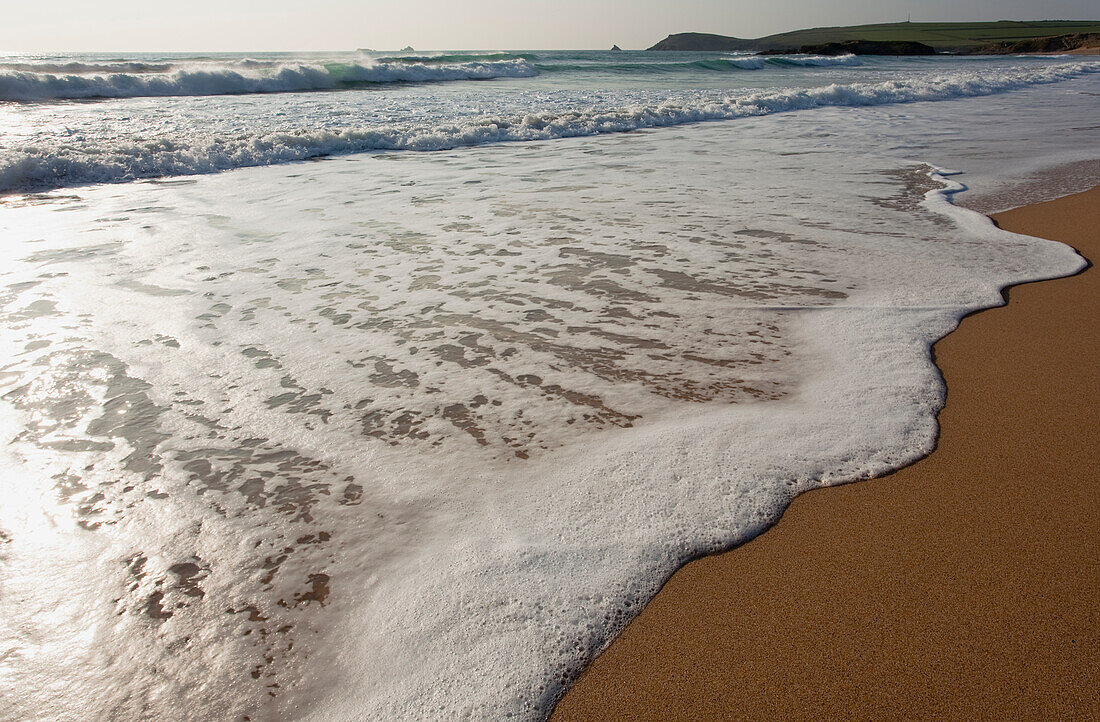 Close-up of foamy surf lapping the sandy shore at Constantine Bay Beach near Padstow; Constantine Bay, Cornwall, England, Great Britain