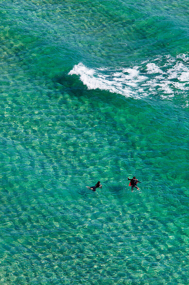 Two people swimming in the shallows off Pen-y-Vaunder Beach, seen from the cliffs at Treen near Penzance; Cornwall, England, Great Britain