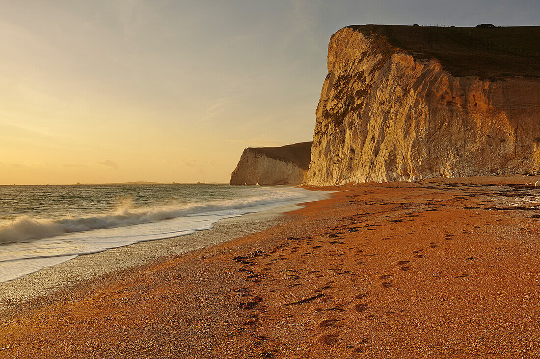 Footprints in the sand and Limestone cliffs near Durdle Door looking towards Weymouth on the Jurassic Coast; Dorset, England, Great Britain