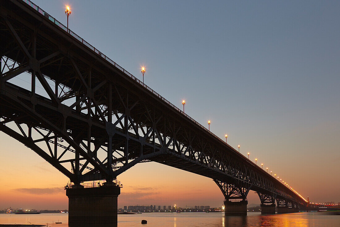Silhouette der Jangtse-Brücke, die den Fluss Jangtse überquert, beleuchtet in der Dämmerung; Nanjing, Provinz Jiangsu, China