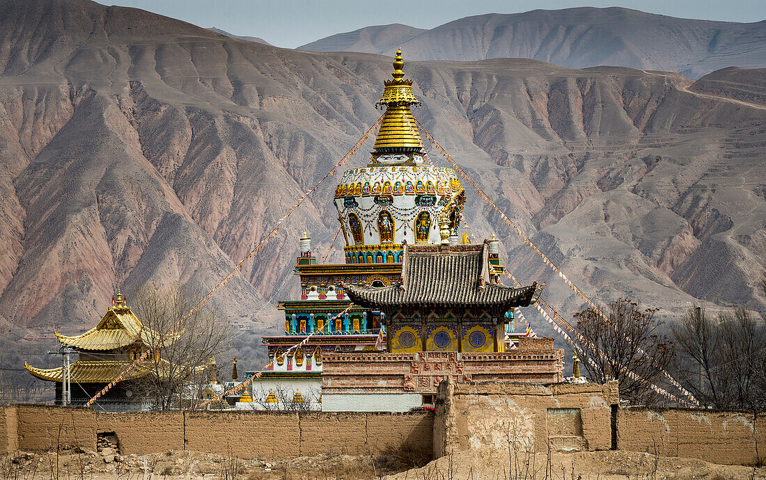 Das Dach eines buddhistischen Tempels im Labrang-Kloster mit den Bergkämmen des Himalaya im Hintergrund; Labrang, Amdo, Tibet