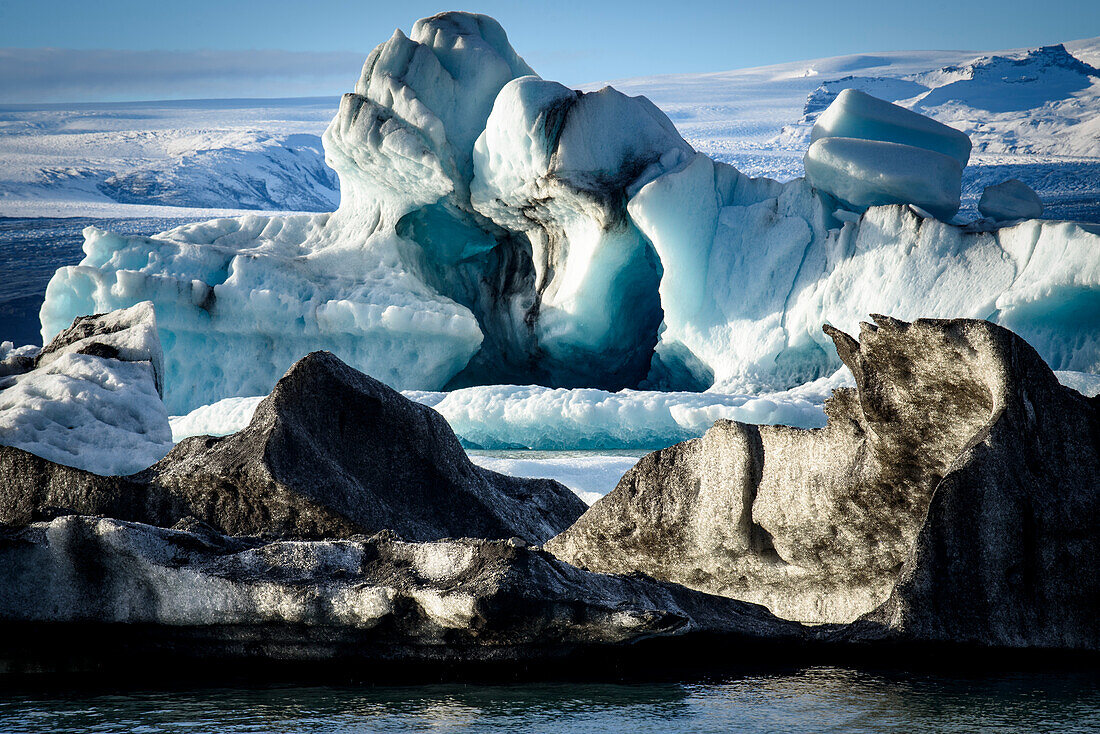 Schwarze und blaue Eisbergformen entlang der Küste der Jokulsarlon Gletscherlagune; Vatnajokull Nationalpark, Island