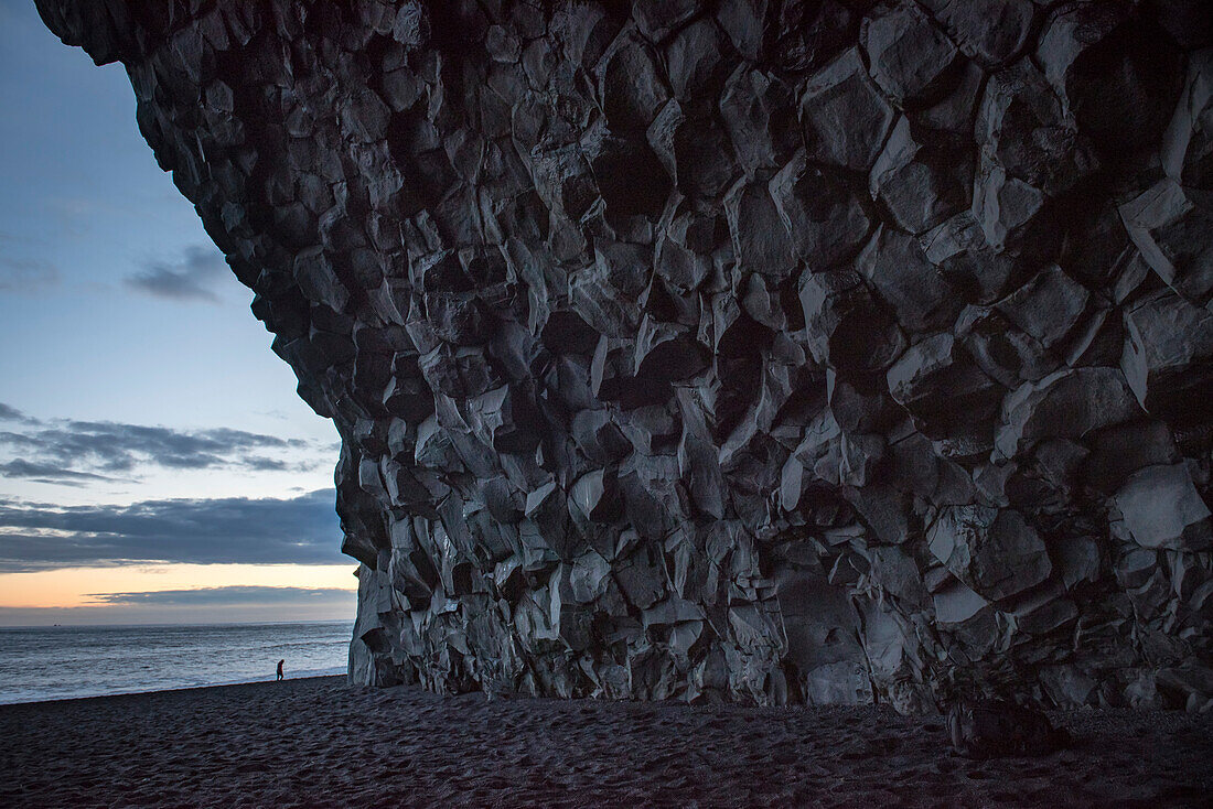 Granithöhle in den Klippen am schwarzen Sandstrand, Reynisfjara Beach, an der Südküste Islands, nahe der Stadt Vik, in der Dämmerung; Island