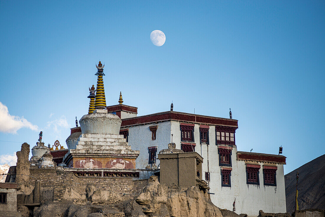 Closer view of the Tibetan Buddhist Lamayuru Monastery on a clifftop at sunset in Lamayouro of the Leh District in the Ladakh Region, with the moon appearing in the blue sky; Jammu and Kashmir, India