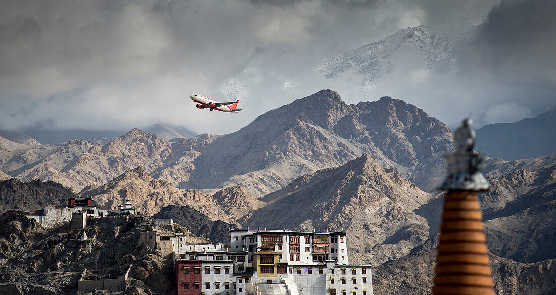 Airplane in flight over the Tibetan Buddhist, Spituk Monastery and the jagged mountaintops of the Himalayas; Jammu and Kashmir, India