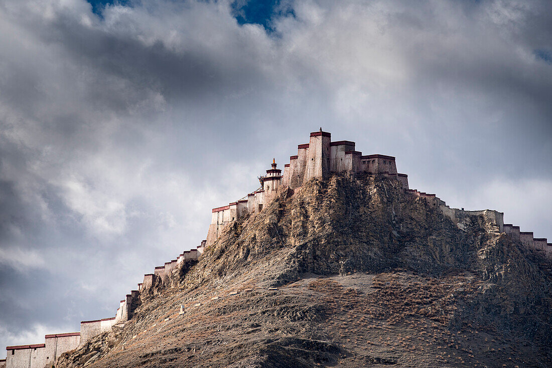 View of the ancient Gyantse Dzong, mountaintop fortress, from Pelkor Chode Monastery, under a stormy sky; Gyantse, Tibetan Autonomous Region, Tibet