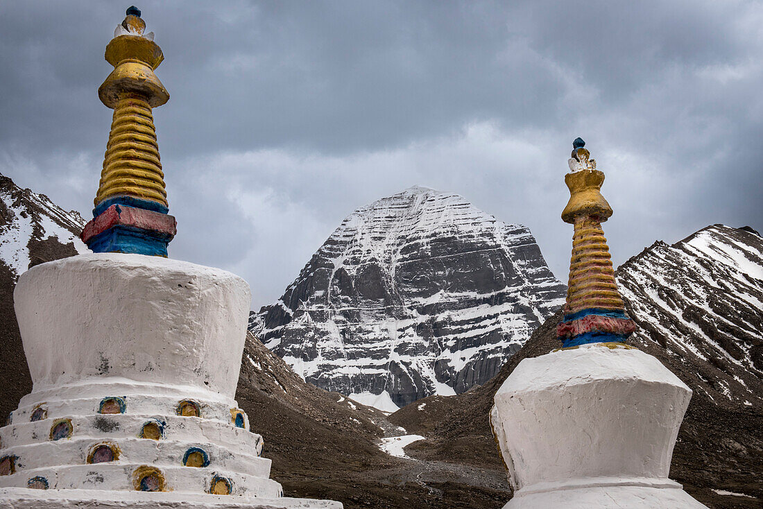 Blick auf den schneebedeckten Mount Kailash, die Axis Mundi, Zentrum der Welt, mit Stupa-Zinnen im Vordergrund; Landkreis Burang, Präfektur Ngari, Autonome Region Tibet, Tibet