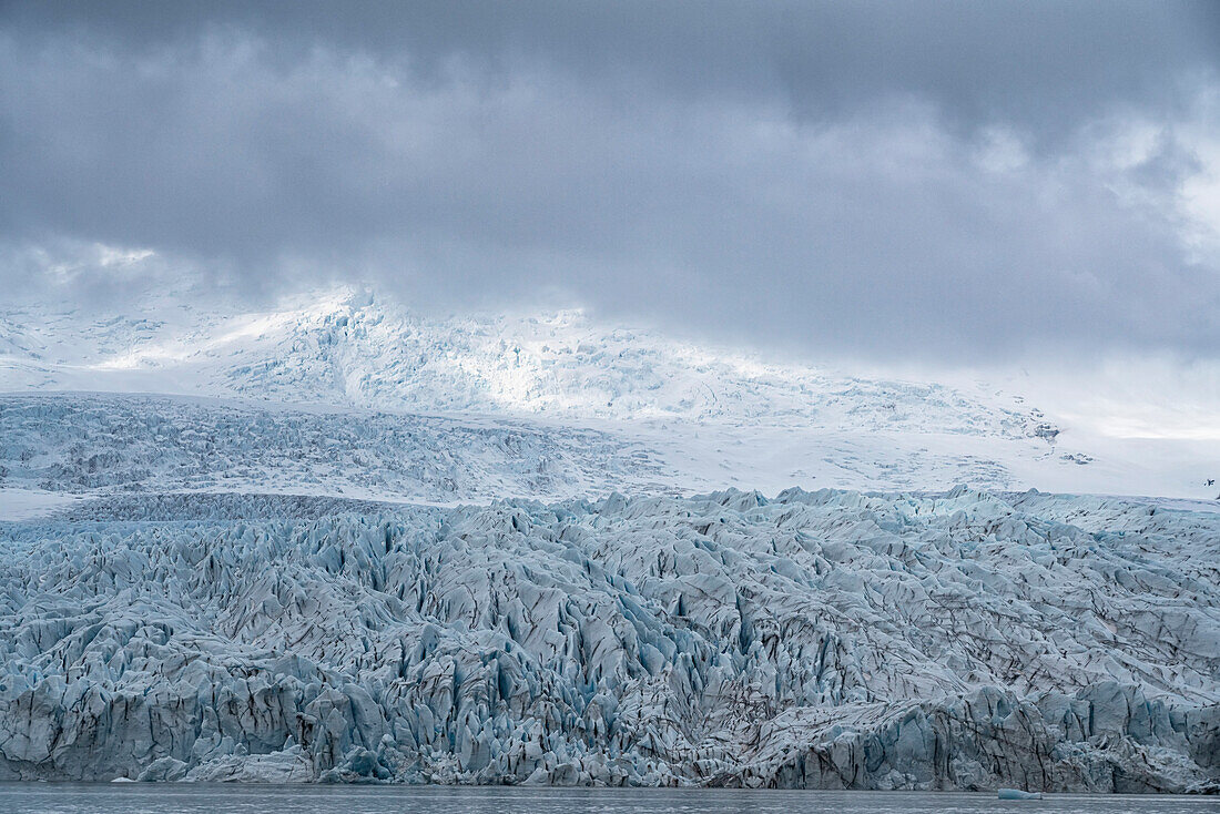 Das blaue Eis des Fjallsjokull Glacier Terminus hebt sich von den grauen, nebligen Wolken ab, aufgenommen von der Fjallsarlon Glacier Lagoon am südlichen Ende des berühmten isländischen Gletschers Vatnaj?l in Südisland; Südisland, Island