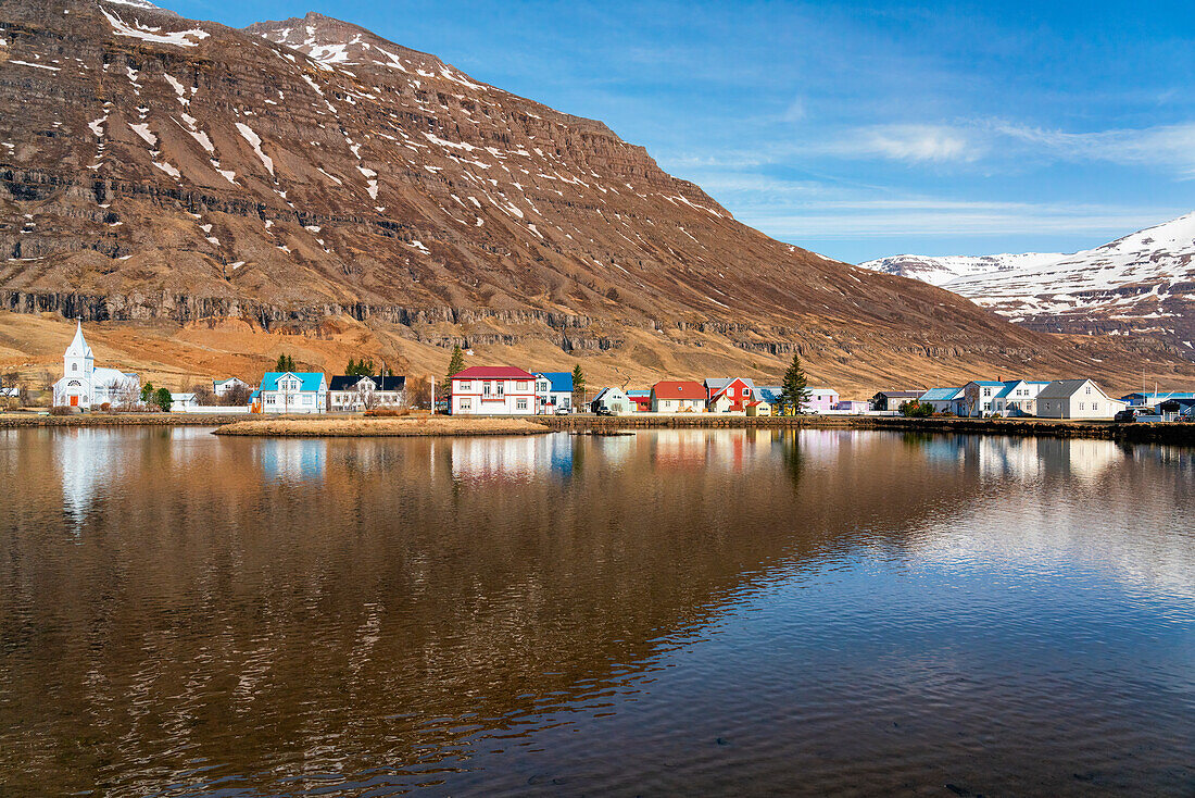 Close-up scenic view of the town of Seyðisfjörður (Seydisfjordur) reflected in the calm water; East Fjords, East Iceland, Iceland