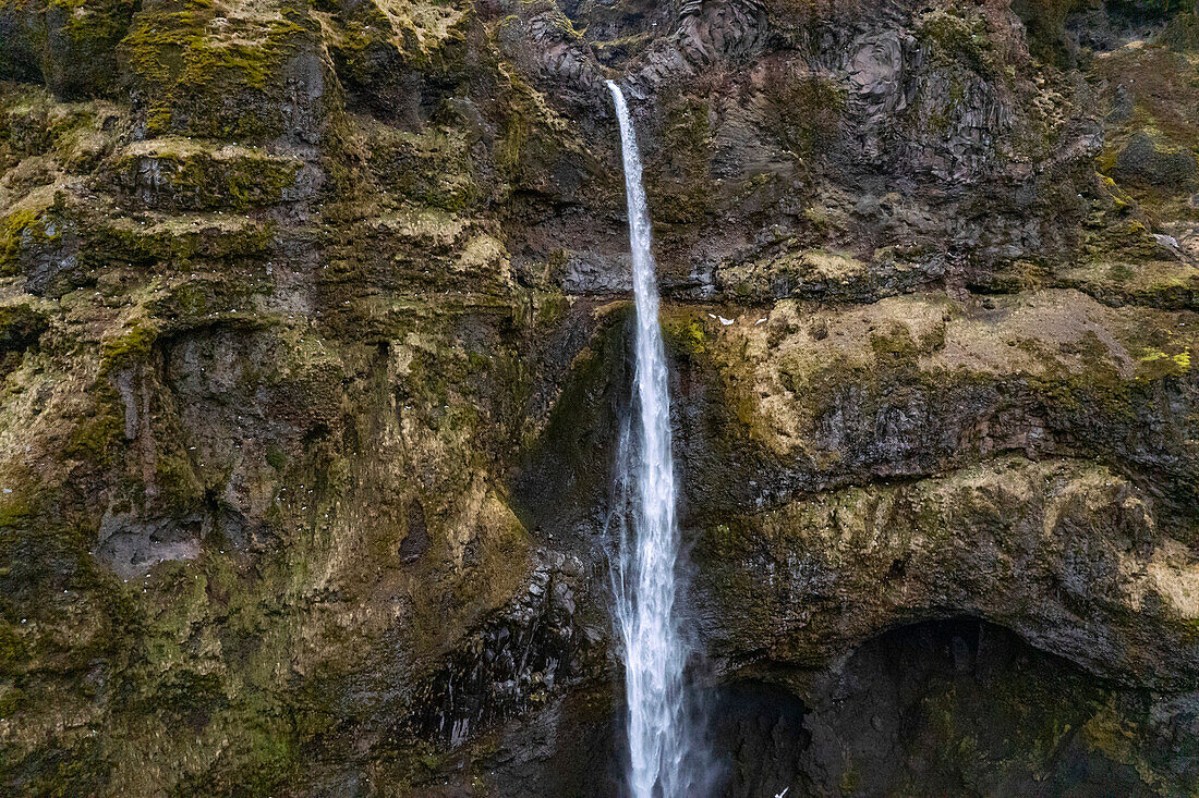 Nahaufnahme eines stürzenden Wasserfalls gegen die felsigen Klippen im Wanderparadies der Mulagljufur-Schlucht; Südisland, Island
