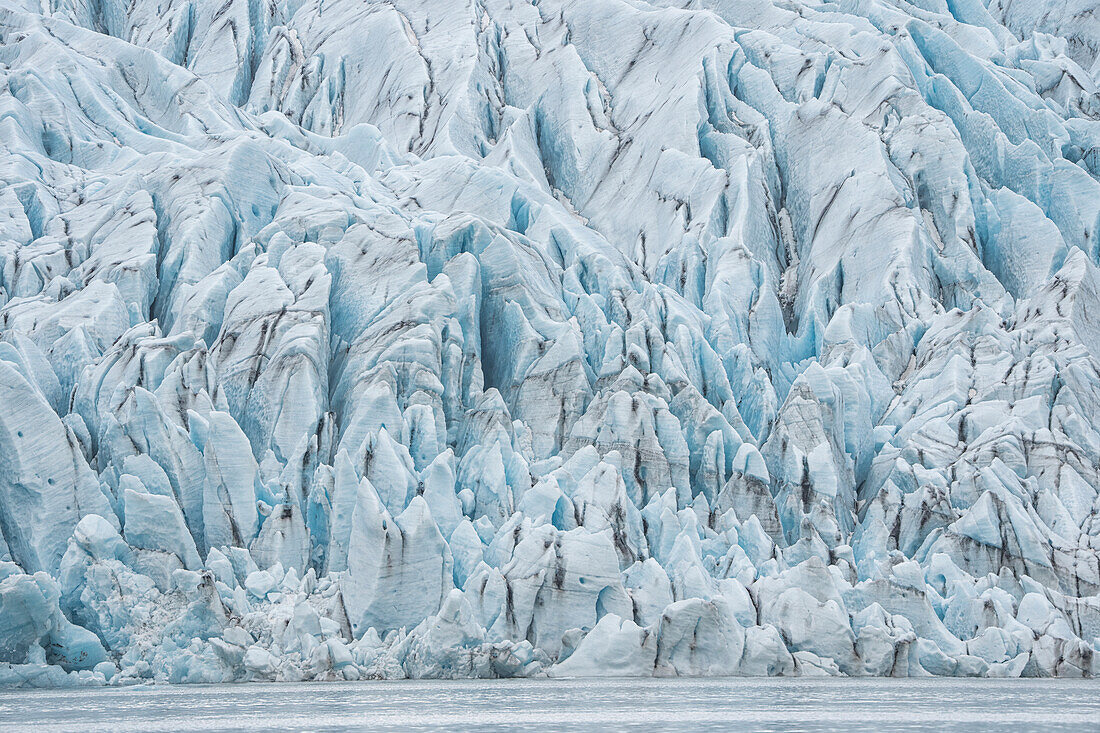 Atemberaubender Blick auf die von Schlick durchzogenen, zerklüfteten blauen Eisformen eines Gletscherendpunktes; Südisland, Island
