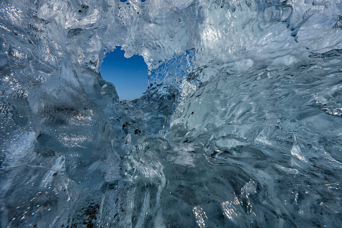 Loch im Eis mit Blick in den blauen Himmel in Südisland; Island