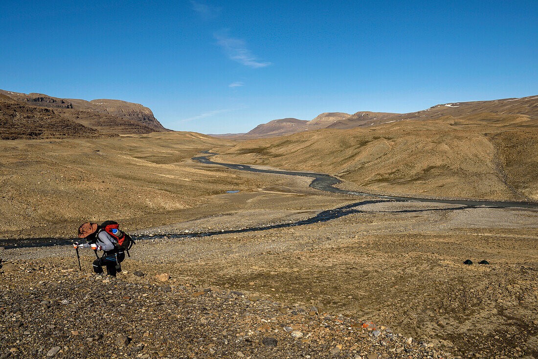 Female team member of a climate change expedition in Greenland is hiking from the base camp on the shore of Centrum So down Grottedalen to explore the valley of caves; Greenland