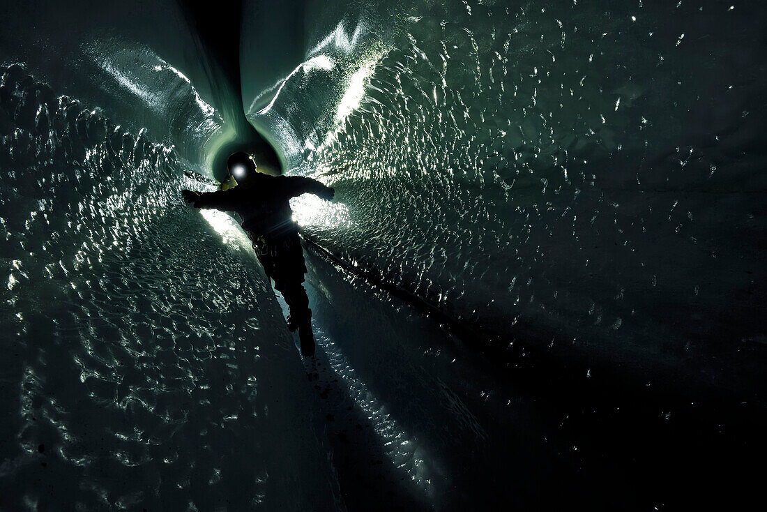 A cave explorer and glaciologist traverses through a tunnel below the surface of the Gorner Glacier.