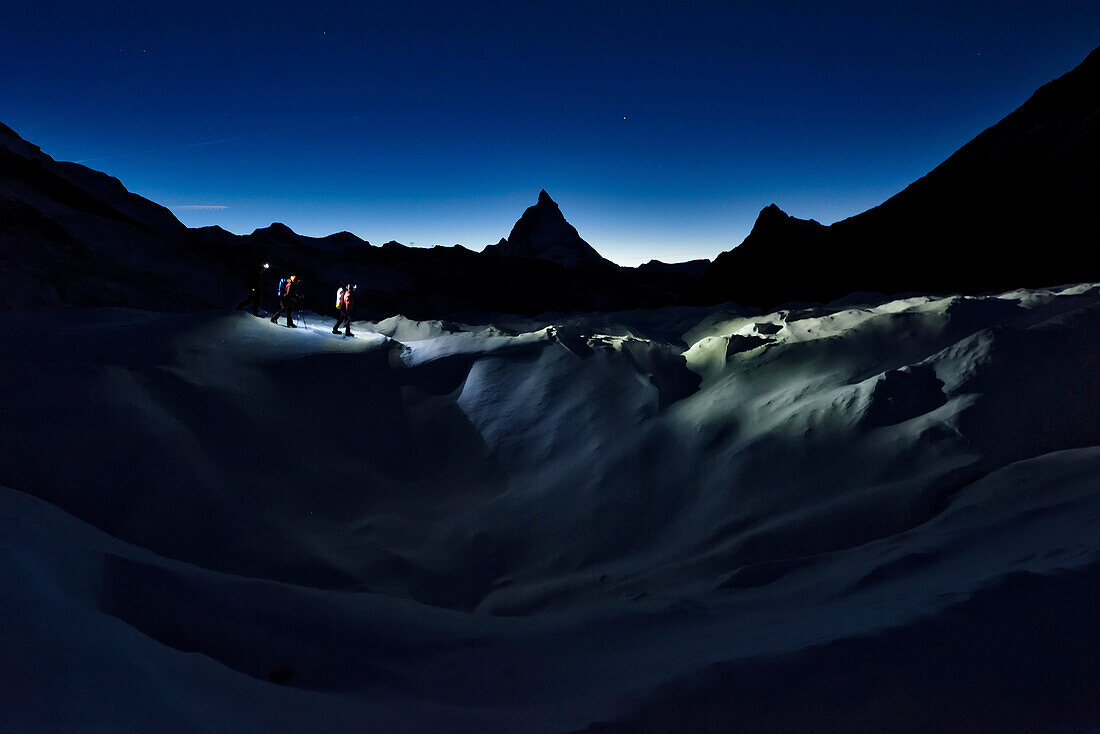 The Matterhorn looms above cave explorers hiking on Gorner Glacier.