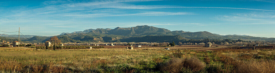 Ländliche Szene von Ackerland mit Bauernhäusern und Bergen im Hintergrund; Benissanet, Tarragona, Spanien