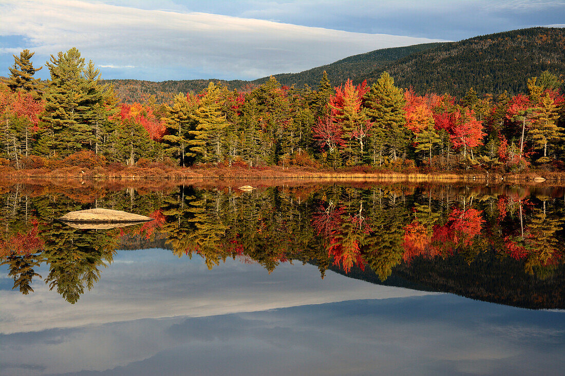 Blick auf Bäume und Hügel, die sich im stillen Wasser eines Teiches im Herbst spiegeln; Bartlett, New Hampshire, USA.