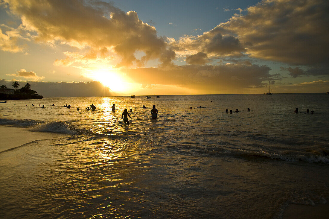 Menschen im Meer der Store Bay bei Sonnenuntergang, Tobago; Tobago, Republik Trinidad und Tobago