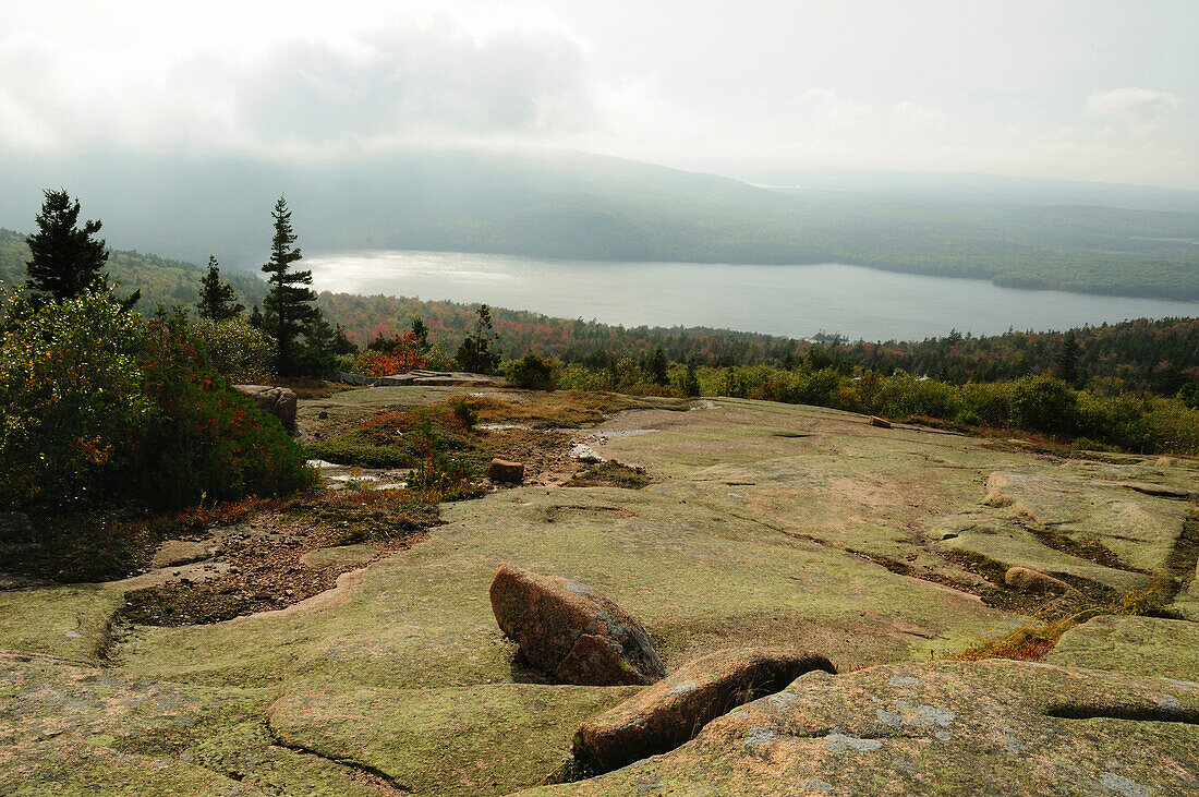 Blick von einem felsigen Abhang des Cadillac Mountain auf einen entfernten See; Acadia National Park, Mount Desert Island, Maine.