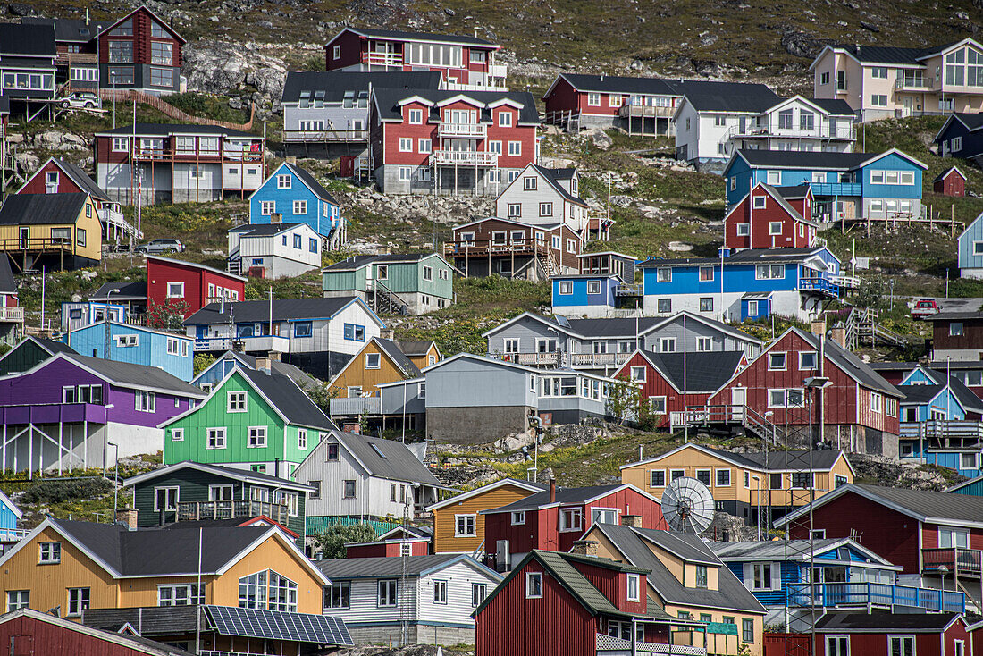 Close-up view of the colorful buildings on the rocky cliffs along the shore in the seaport town of Qaqortoq on Greenland's southern tip; Qaqortoq, Southern Greenland, Greenland