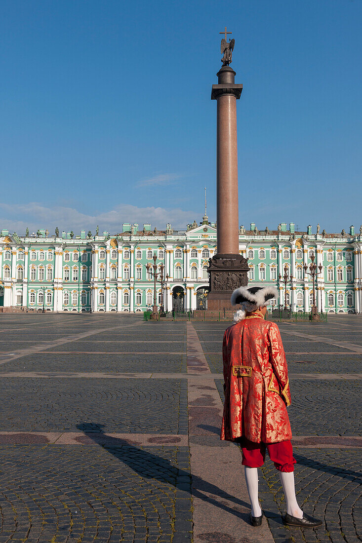 Eine Person in traditioneller Tracht auf dem Palastplatz mit Alexandersäule und Winterpalast; St. Petersburg Russland